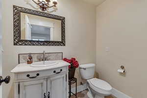 Bathroom with toilet, vanity, backsplash, and baseboards