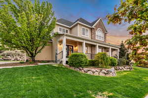 Traditional-style home featuring stone siding, a front yard, and a porch