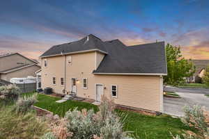 Back of house at dusk featuring central air condition unit, a shingled roof, and entry steps