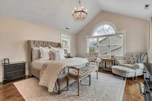 Bedroom featuring a chandelier, wood finished floors, and vaulted ceiling