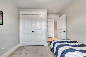 Bedroom featuring light carpet, baseboards, and a closet