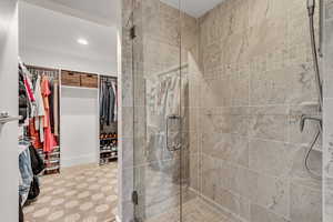 Full bath featuring a stall shower, a walk in closet, and recessed lighting