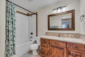 Full bath featuring toilet, shower / tub combo, vanity, and decorative backsplash