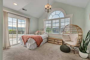Carpeted bedroom featuring access to outside, vaulted ceiling, and a chandelier