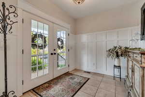 Entryway featuring a decorative wall, french doors, healthy amount of natural light, and a wainscoted wall