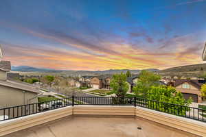 Patio terrace at dusk featuring a residential view, a mountain view, and a balcony
