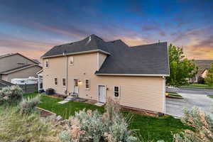 Back of property at dusk featuring a shingled roof and central AC