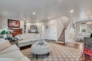 Living room featuring stairway, wood finished floors, baseboards, recessed lighting, and a chandelier