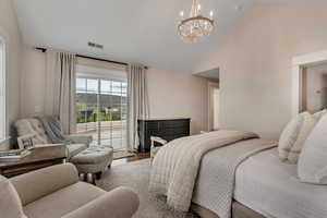 Bedroom featuring access to exterior, a chandelier, wood finished floors, and high vaulted ceiling