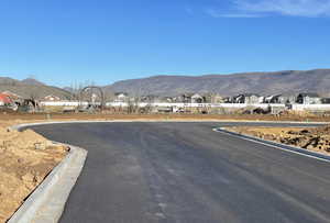 View of asphalt road featuring curbs, a residential view, and a mountain view