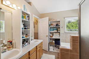 Full bathroom with healthy amount of natural light, lofted ceiling, tile patterned flooring, tile walls, and double vanity