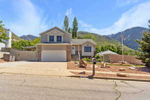 View of front facade featuring a mountain view, an attached garage, fence, concrete driveway, and brick siding