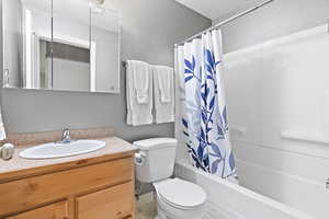 Full bath with toilet, shower / bath combo with shower curtain, and vanity