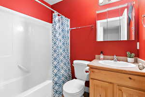 Bathroom with toilet, vanity, and shower / bathtub combination with curtain