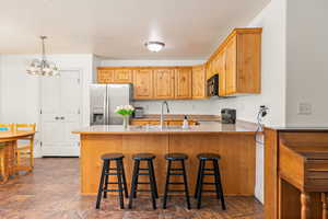 Kitchen with black appliances, a sink, a peninsula, a chandelier, and a kitchen bar