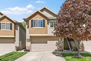 View of front facade featuring stucco siding, concrete driveway, stairway, and an attached garage