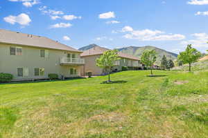 View of grassy yard with a mountain view and a balcony