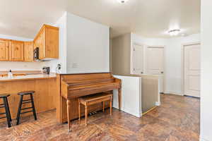 Kitchen with black microwave, stove, a breakfast bar, light countertops, and baseboards