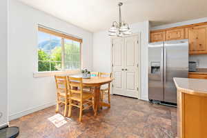 Dining area featuring a chandelier, dark stone finish flooring, and baseboards