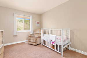 Bedroom featuring carpet flooring, a crib, and baseboards