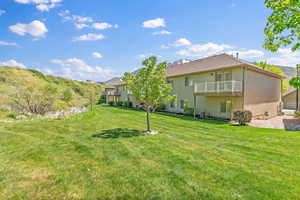 Back of house featuring a balcony, a yard, and stucco siding