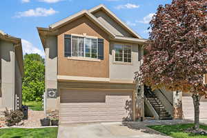 View of front of house featuring stucco siding, a garage, driveway, and stairs