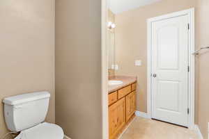 Bathroom with baseboards, vanity, toilet, and tile patterned flooring
