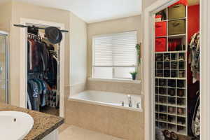 Bathroom featuring a spacious closet, a shower stall, a garden tub, and vanity