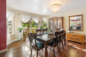 Dining room featuring wood-type flooring, a chandelier, and baseboards