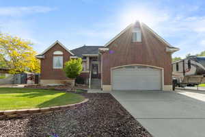 View of front of home with brick siding, concrete driveway, and a front yard