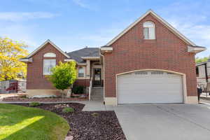Traditional home with driveway, brick siding, a garage, and roof with shingles