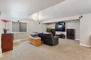 Carpeted living area featuring a textured ceiling and baseboards