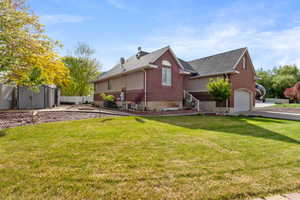 View of side of home featuring brick siding, an attached garage, a shed, an outbuilding, and roof with shingles