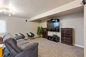 Carpeted living room featuring a textured ceiling and baseboards