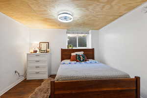 Bedroom with baseboards, wooden ceiling, and dark wood-style floors