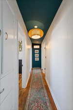 Hallway featuring a textured wall, baseboards, and wood finished floors