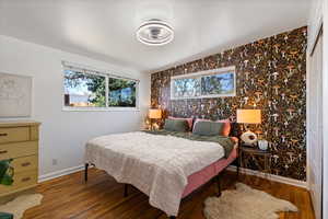 Bedroom with wood finished floors, baseboards, and multiple windows