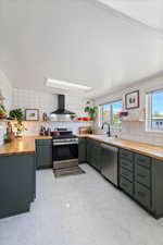 Kitchen featuring backsplash, wall chimney range hood, stainless steel appliances, and butcher block countertops