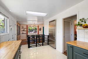Kitchen with butcher block countertops, a chandelier, built in fridge, and green cabinetry