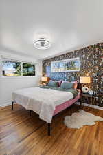 Bedroom with wallpapered walls, wood finished floors, and baseboards