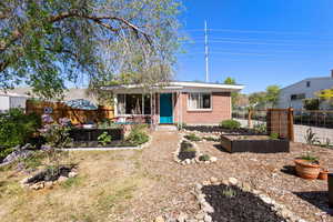 View of front of property with brick siding, a garden, and fence