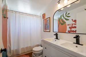Bathroom featuring toilet, double vanity, a sink, and shower / bathtub combination with curtain