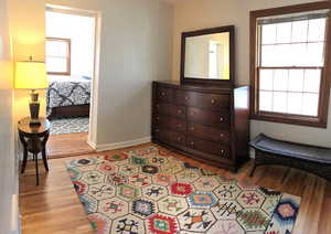Bedroom with wood finished floors, multiple windows, and baseboards