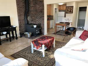 Living room featuring a wood stove, light tile patterned floors, and baseboards