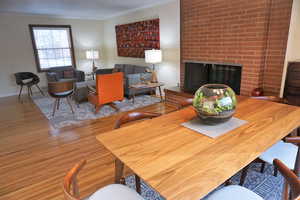 Living room with wood finished floors, a fireplace, ornamental molding, and baseboards