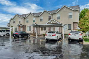 Multi unit property featuring covered parking, stucco siding, and roof with shingles