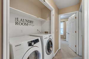Washroom with separate washer and dryer, light carpet, and baseboards