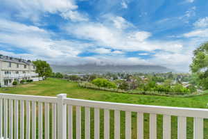 View of grassy yard featuring a mountain view and a balcony
