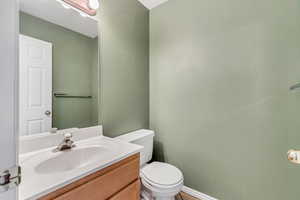 Half bath with toilet, vanity, and baseboards