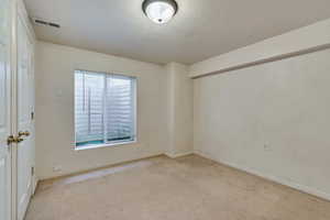 Spare room with light carpet, baseboards, and a textured ceiling